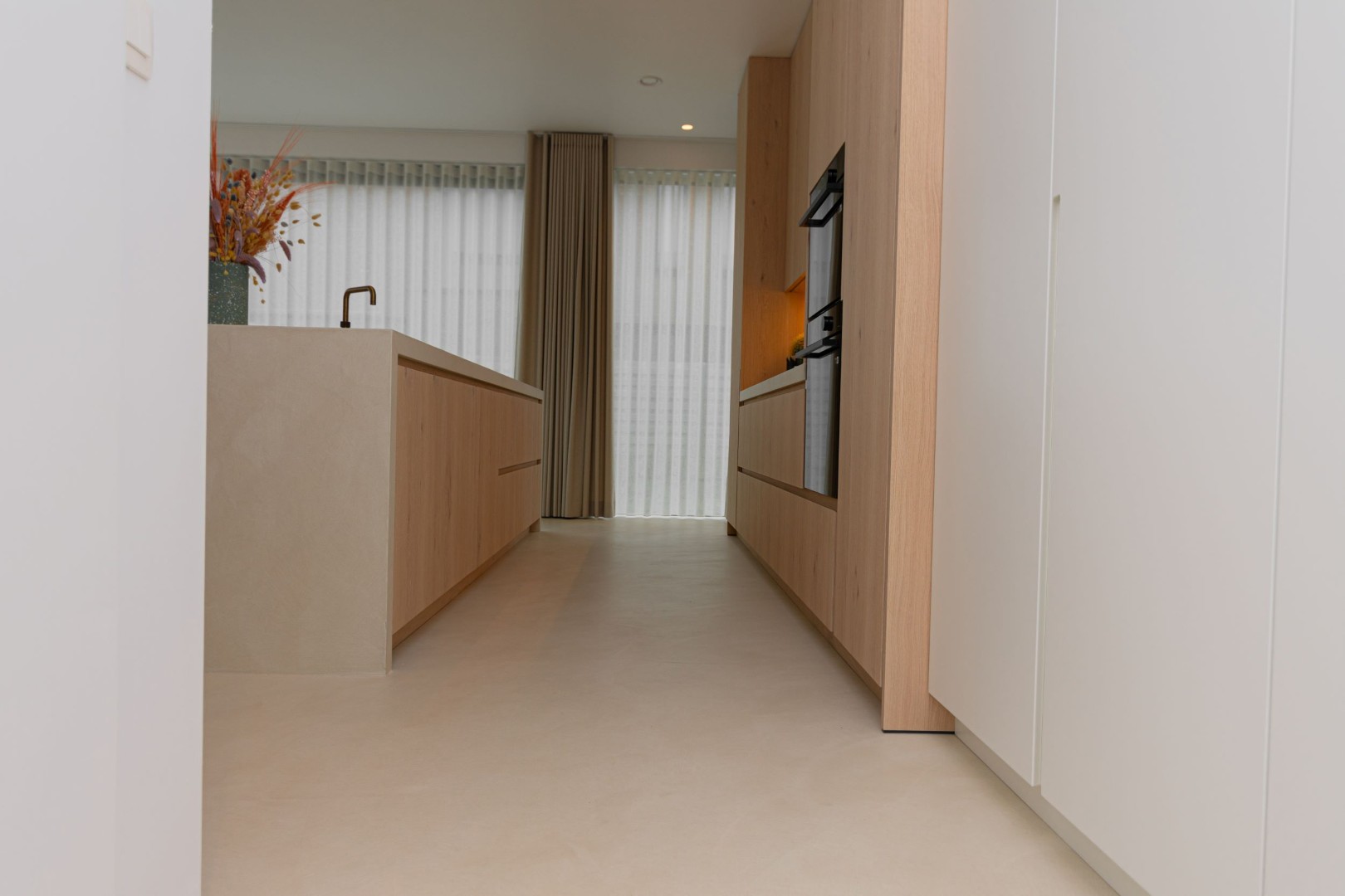 Stijlvoorbeeld gietvloer smalle keuken doorkijk met houten kasten