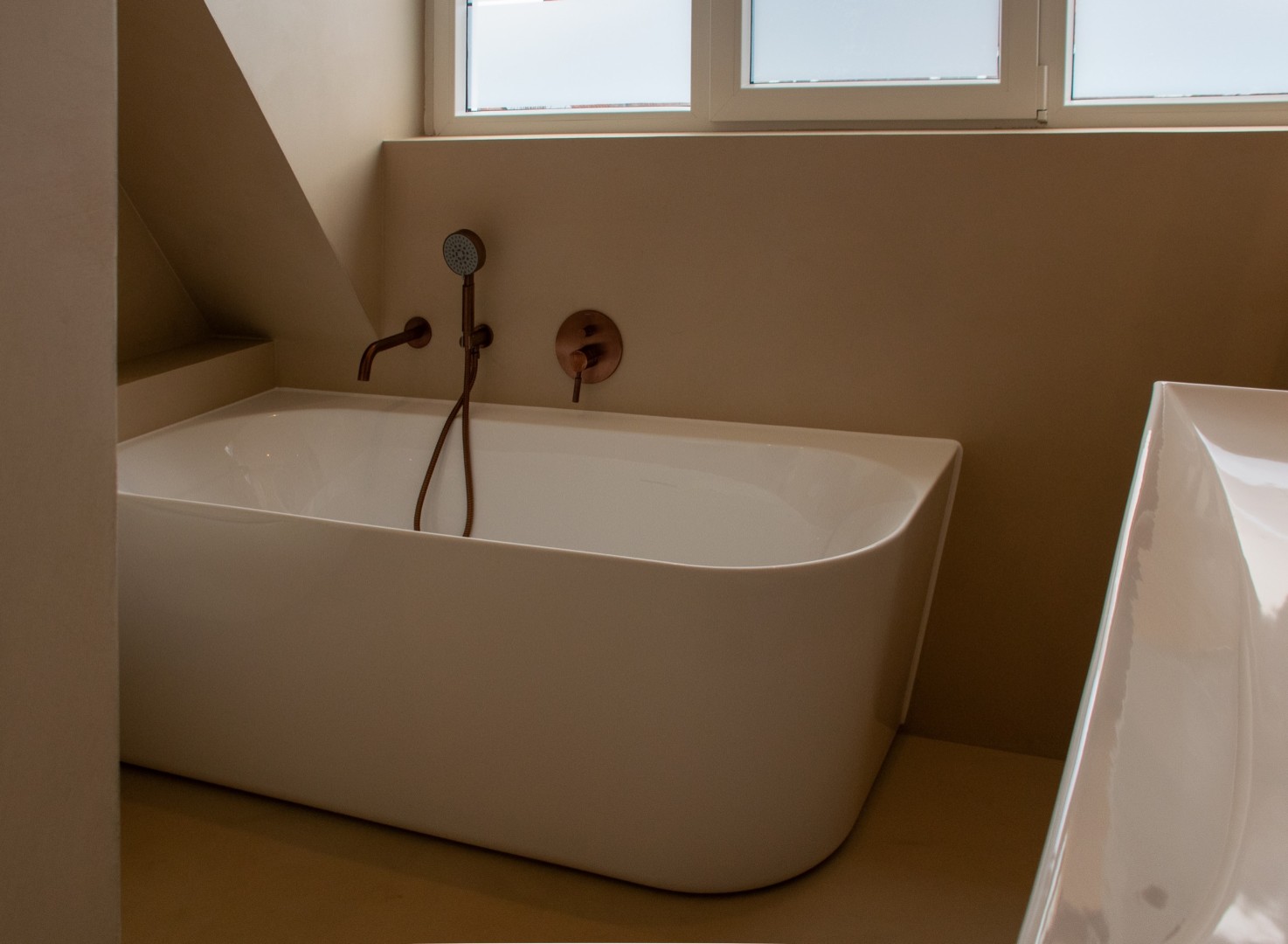 Stijlvoorbeeld microcement badkamer bad met koperen kraan