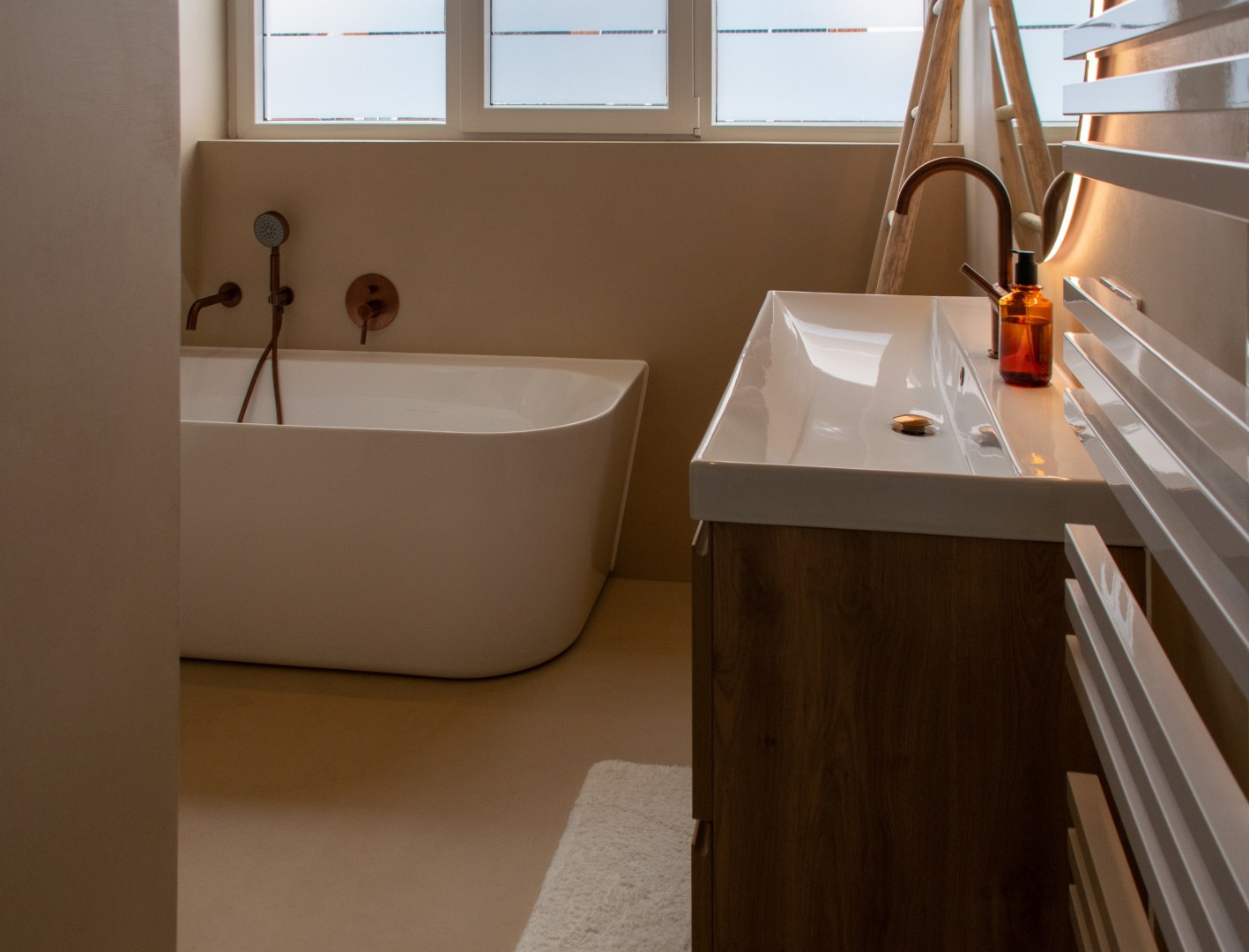 Microcement badkamer met vrijstaand bad en wastafel in betonlook