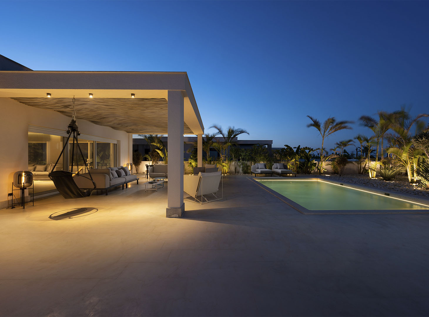 Stijlvoorbeeld microcement buitenterras villa bij zwembad in avondsfeer