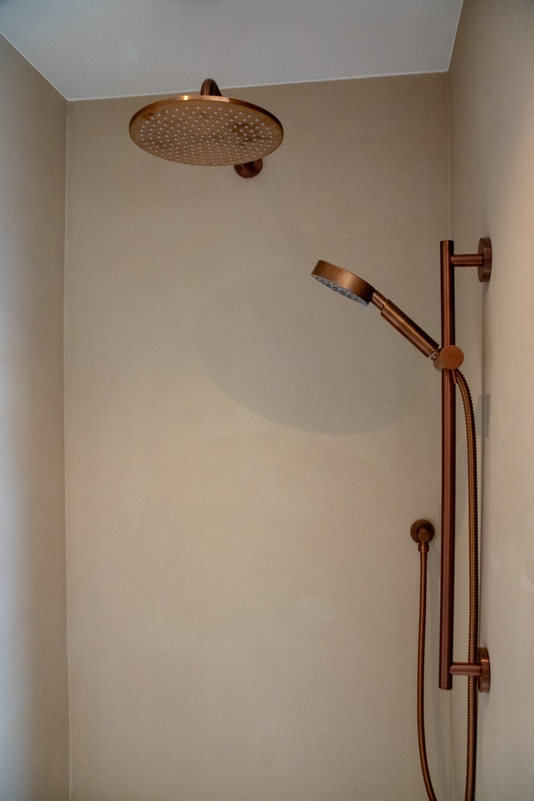 Microcement inloopdouche betonlook met koperen regendouche