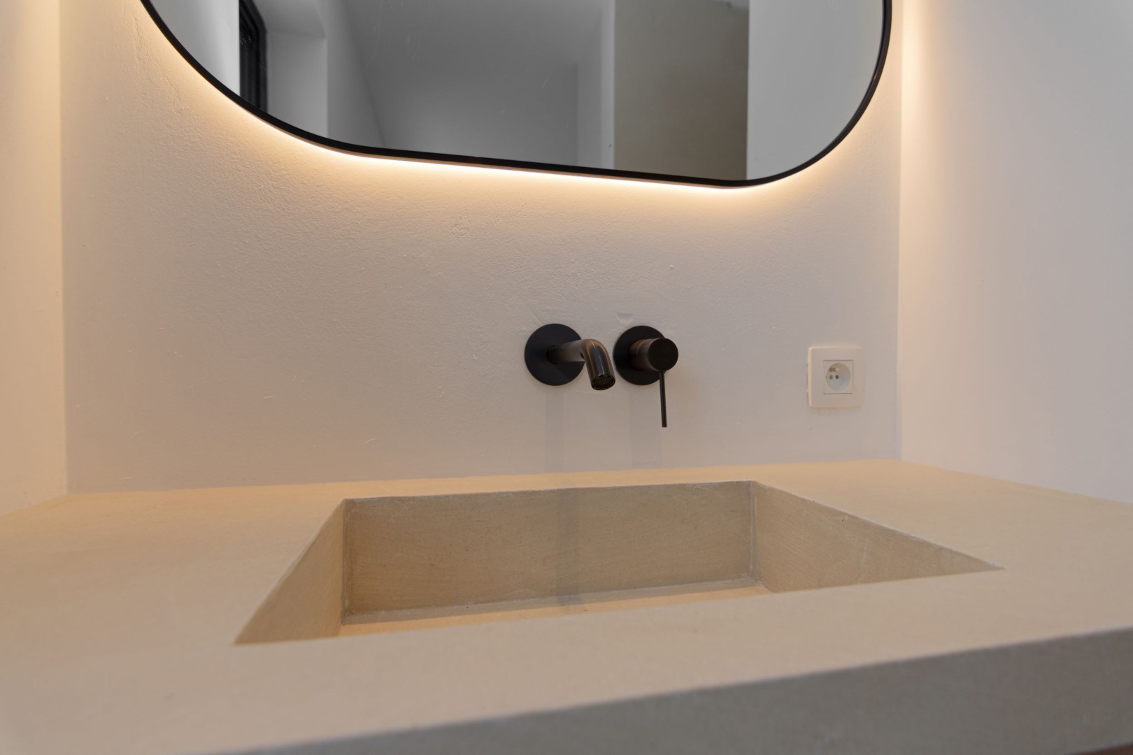 Stijlvoorbeeld microcement ingebouwde wastafel met zwarte kraan