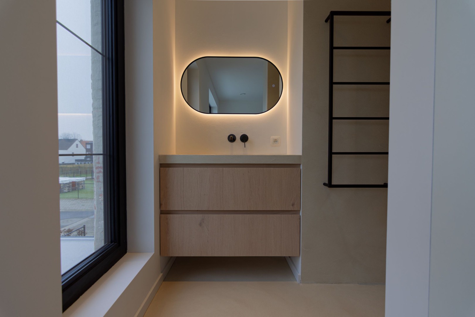 Stijlvoorbeeld microcement wastafelmeubel hout naast raam